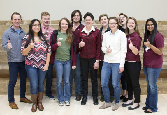 Group photo of Dr. Corrie Brown and Global One Health students giving the Aggie gig 'em hand sign