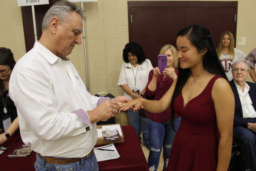 Angelica's father places her ring on her finger during this year's Aggie Ring Day.