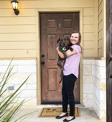 Allie stands in a doorway holding her puppy Mack