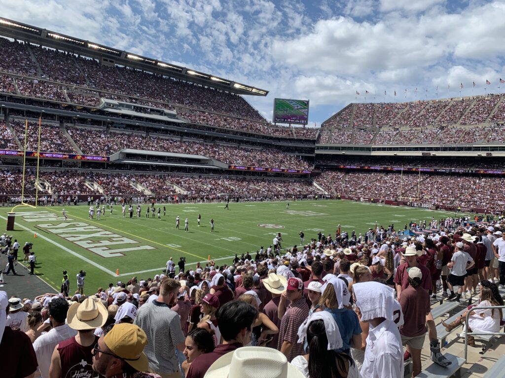 Thousands of fans dressed in maroon and white cheering on the Texas A&M Aggies at Kyle Field.