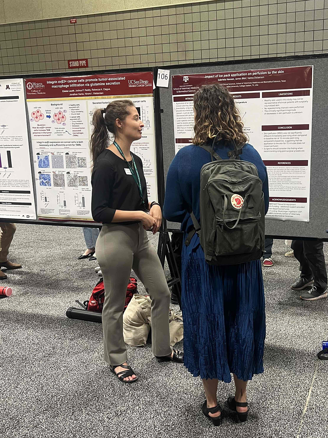 Gabriela explaining her research poster to a symposium attendee