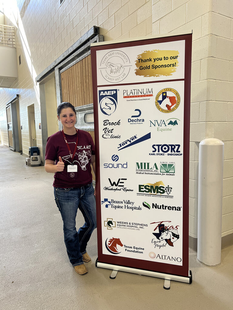 Allie stands next to tall promotional banner inside a barn