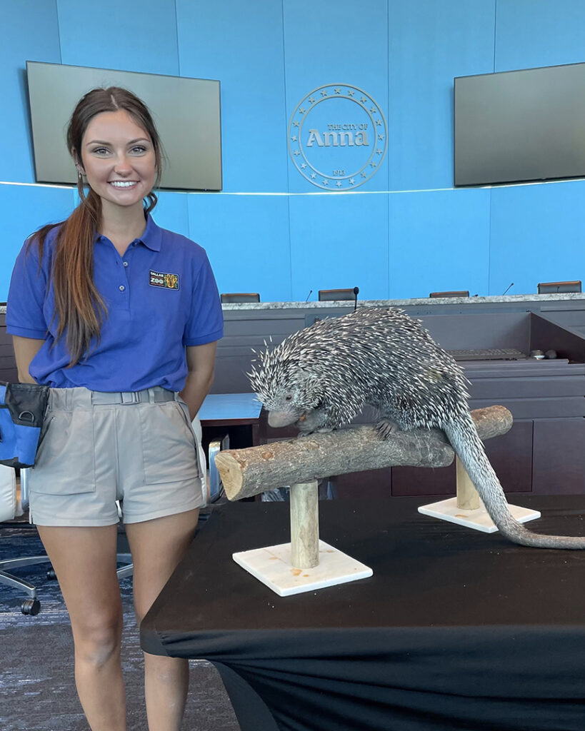 Claire stands smiling with a porcupine in a conference room.
