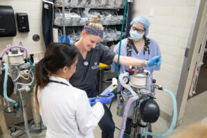 Techs and clinicians around an anesthesia machine