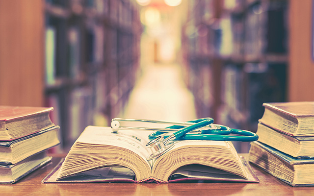 Old books in medical library with a stethoscope resting on an open book