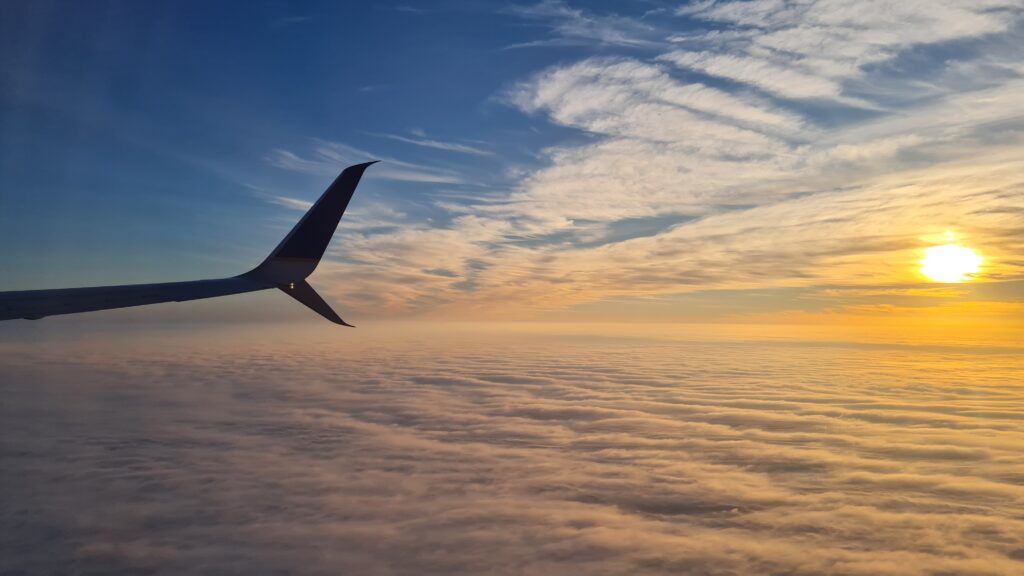 Wing of airplane at sunrise over cloud cover above the Gulf of Mexico