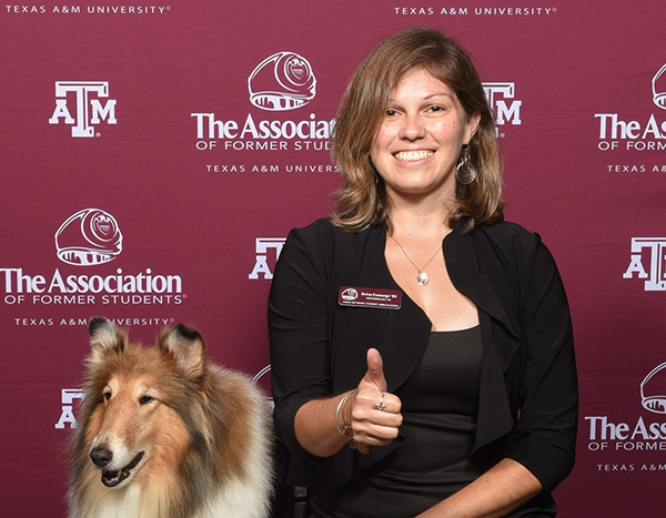 Krisa Camargo and Reveille in front of a maroon Texas A&M Association of Former Students background