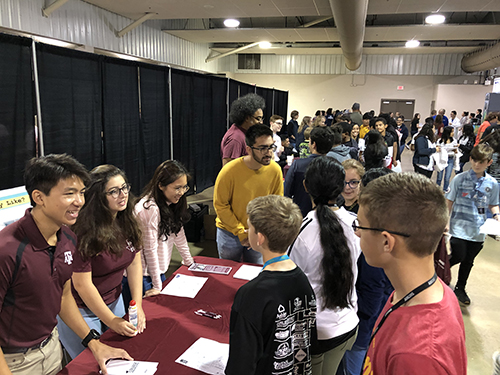 Texas A&M PEER student fellows talking to kids at a booth