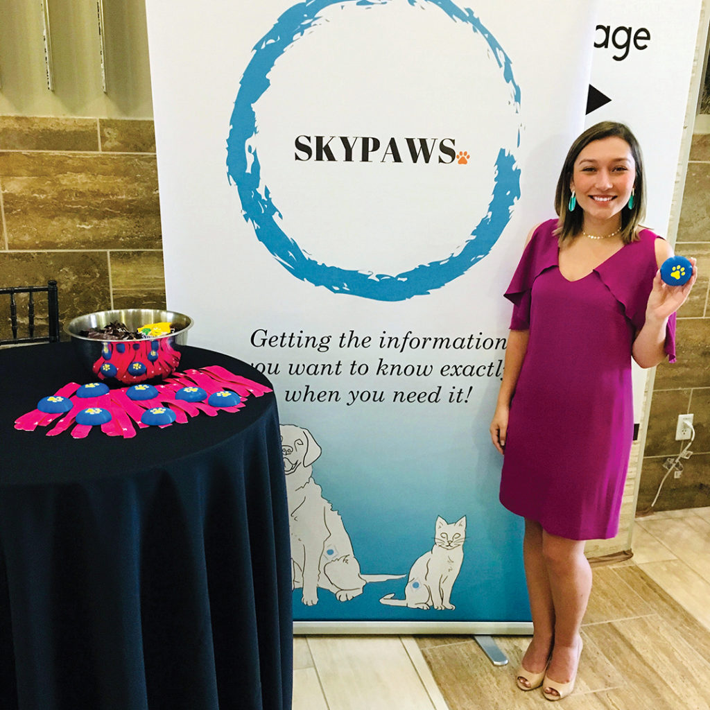 Young holding up a skypaws device in front of a skypaws banner