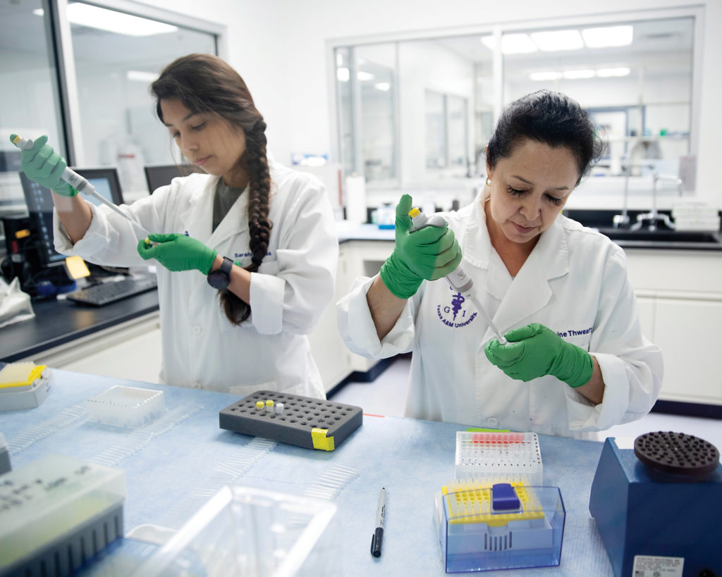 two women in white lab coats pipetting