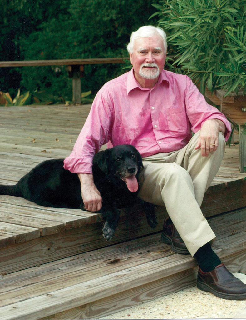 man and black lab Jetty sitting on a deck