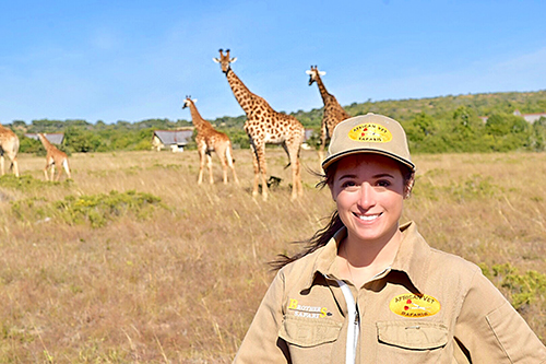 Rachel Ellerd in safari attire with giraffes in the background