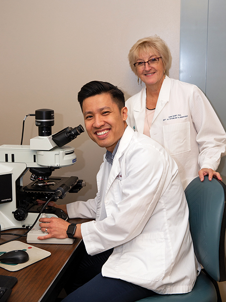 Duc Nguyen and Dr. Dana Gaddy next to a microscope