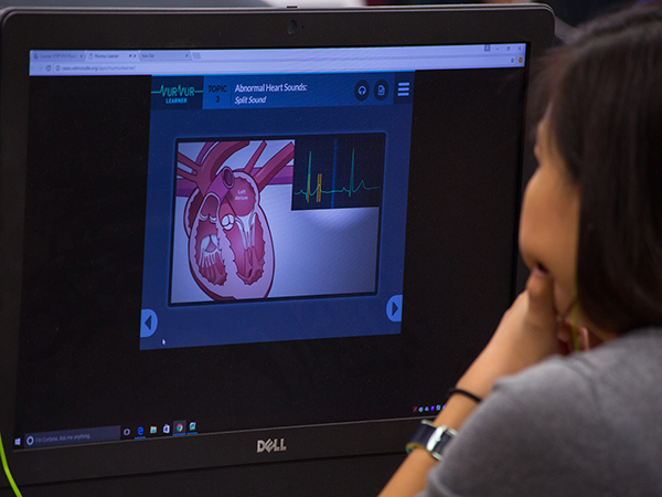 A female student view her computer screen, which shows a learning module about heart rhythms
