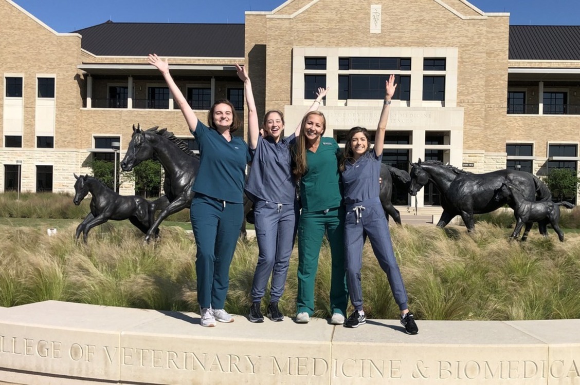 four female veterinary students celebrate in front of the VBEC complex