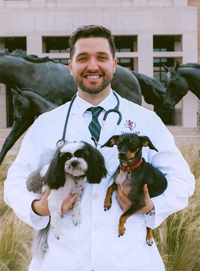 Daniel Anthony in a white coat holding two dogs