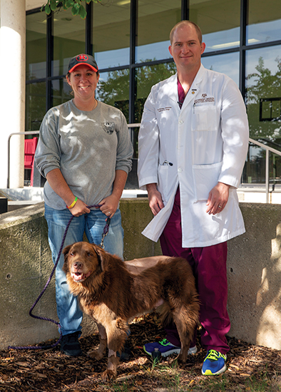 Rachael Crivelli, Dr. Brandan Wustefeld-Janssens, and Remington outside the Texas A&M Small Animal Hospital