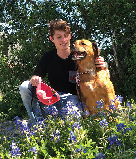 Cannon Lenfield hugs his brown dog Liberty in a field of bluebonnets
