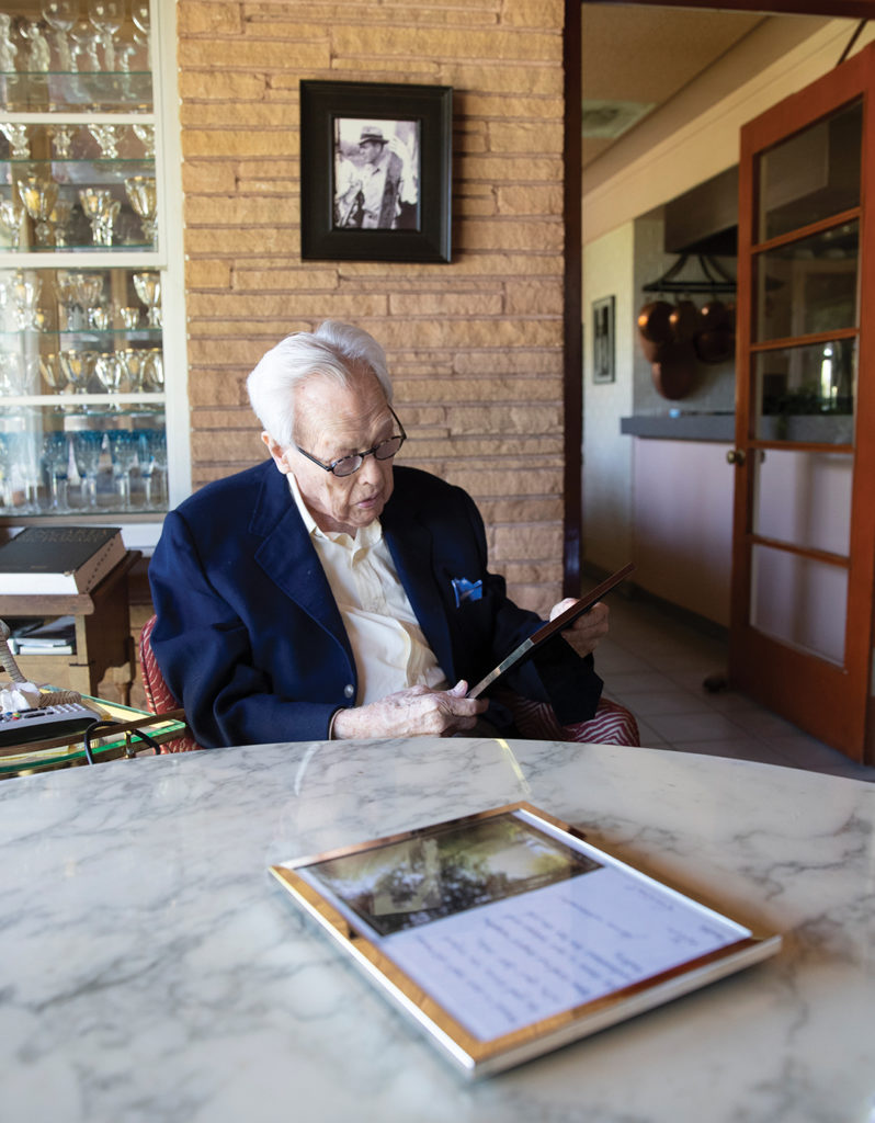 Tex Moncrief sitting at a table reading a framed letter
