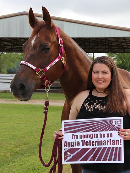 Santana, a brown horse, next to Chloe Bening holding up a sign reading "I'm going to be an Aggie veterinarian!"