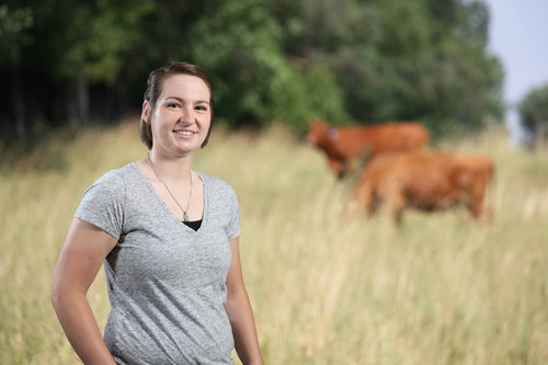 Dr. Jenna Funk in a field with cattle
