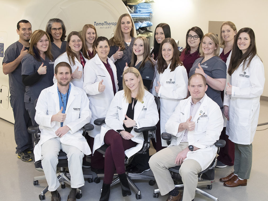 A group of veterinarians and veterinary technicians from the texas A&M oncology service give thumbs up 