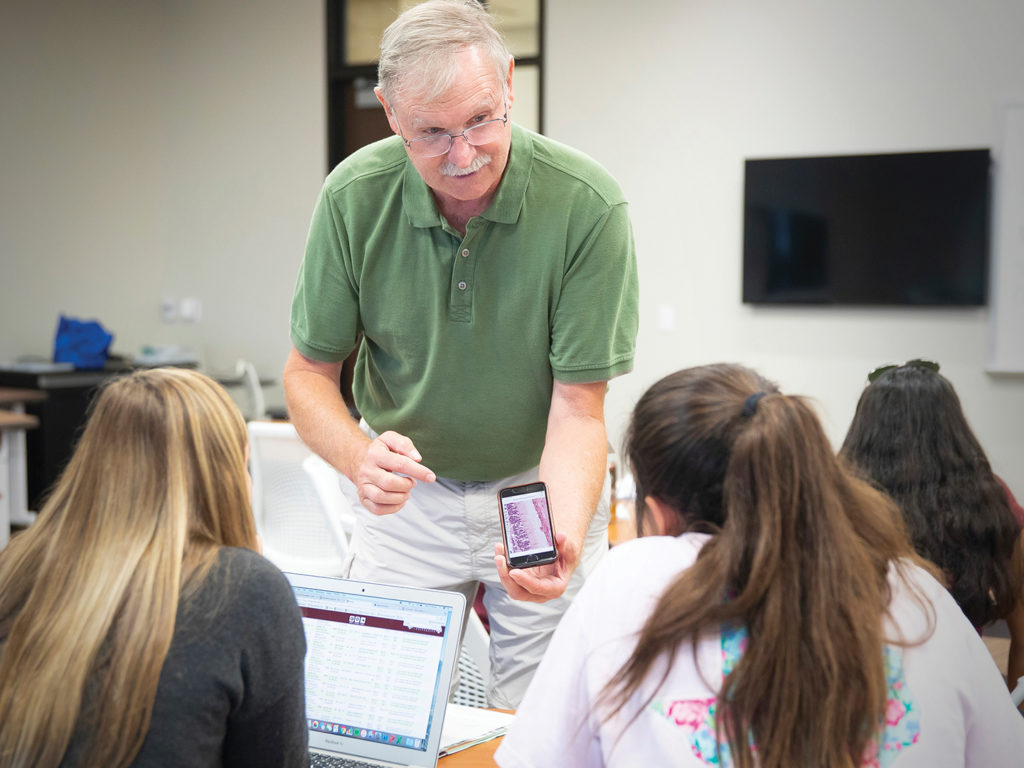 Dr. Larry Johnson shows students an image of a cell on a phone