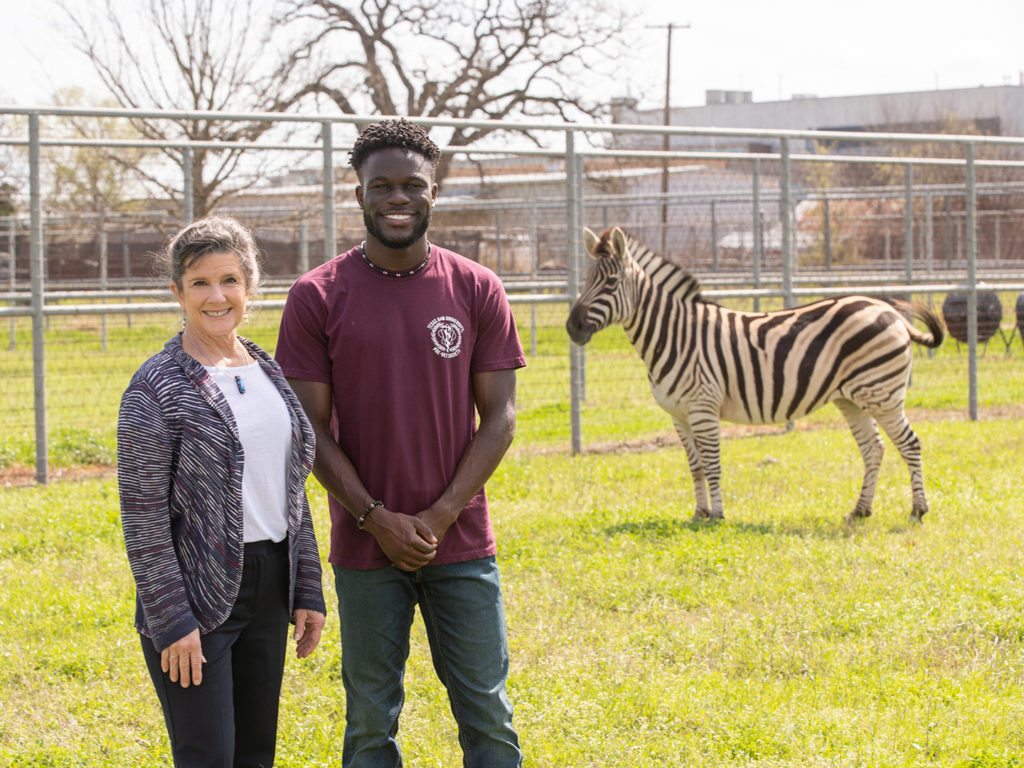 Dr. Alice Blue-McLendon and Warren with a zebra in the background