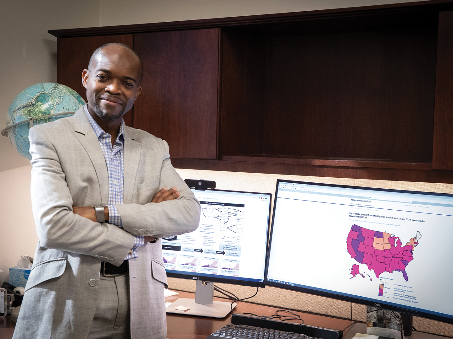 Dr. Martial Ndeffo in his office, with a COVID-19 response model on the computer screen