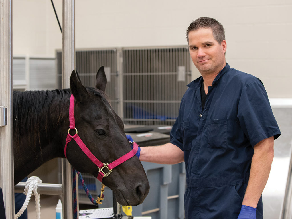 Chris Tiller petting a black horse