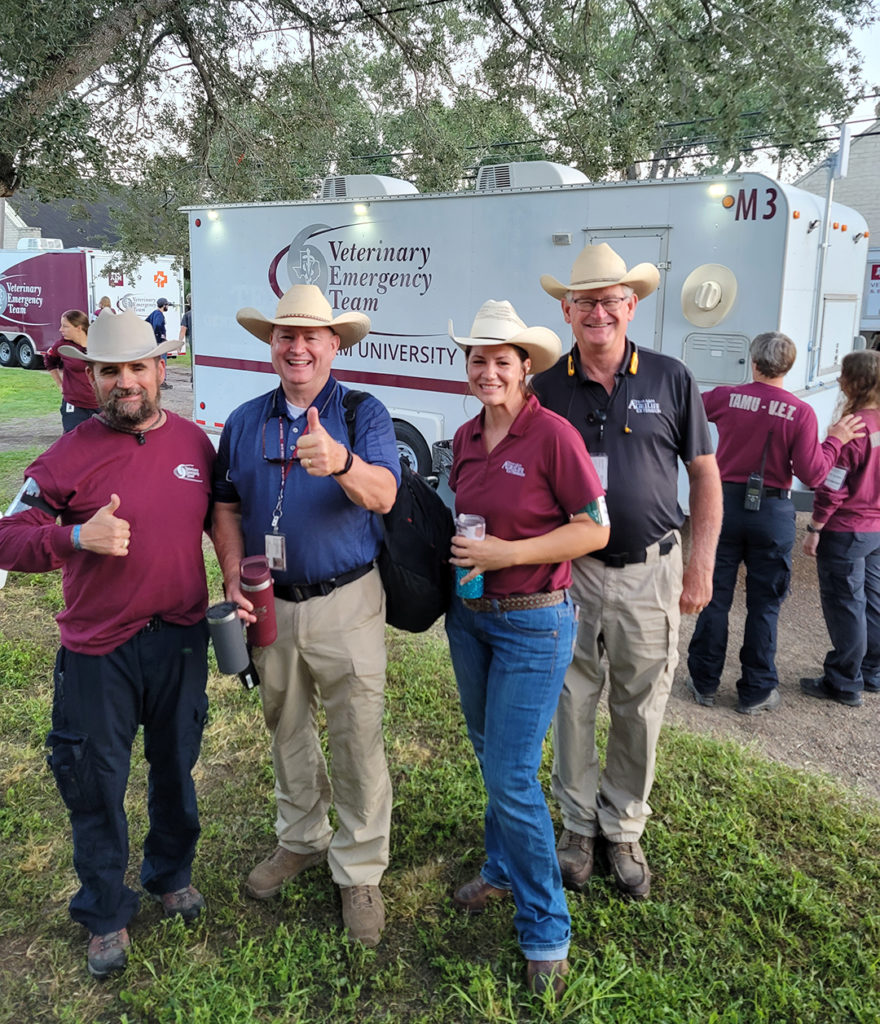 four people in cowboy hats in front of the Texas A&M vet trailer at Operation Lone Star