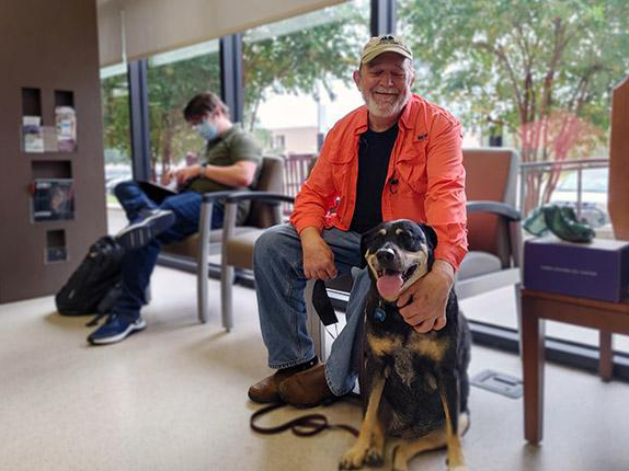 A man and mixed breed dog in the Small Animal Teaching Hospital lobby