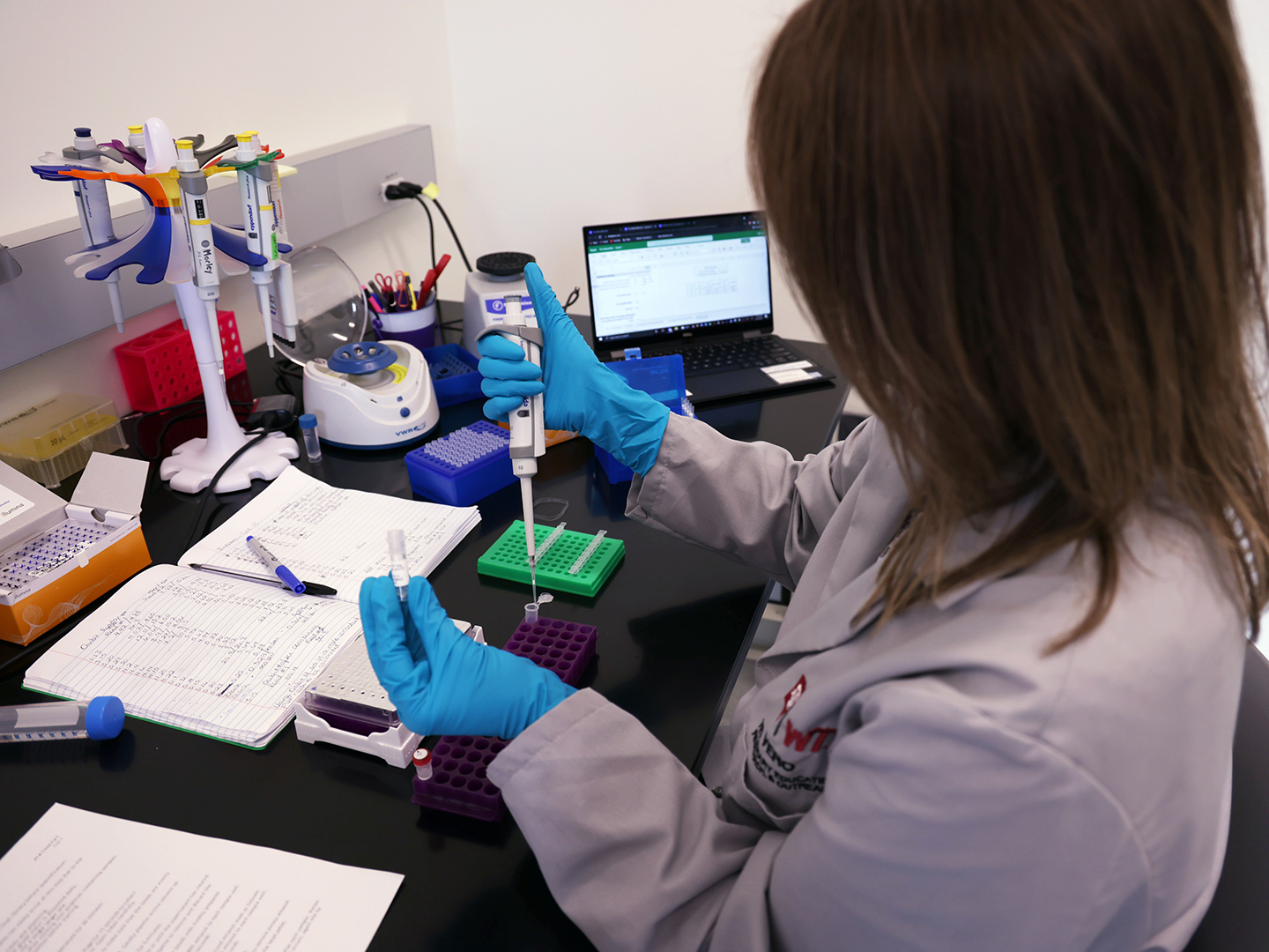 researcher in white coat working with pipette in VERO lab