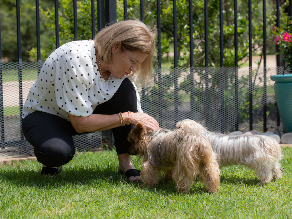 Bickie Coffey petting her small dogs in a yard