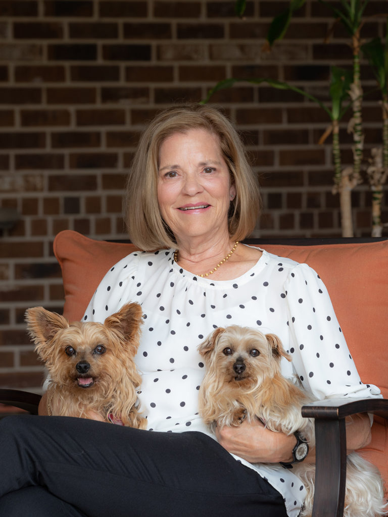 Bickie Coffee sitting holding her two small terrier dogs