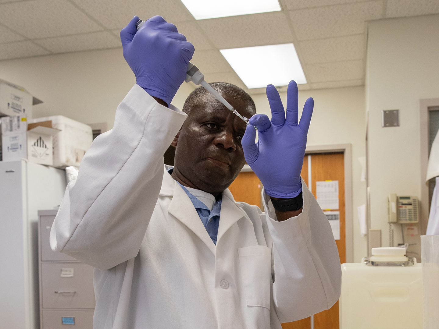 Mulenga measuring a sample with a pipette