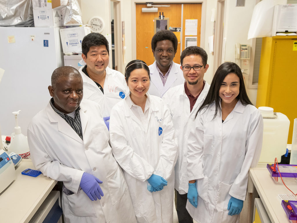 Mulenga and five other lab members in white coats