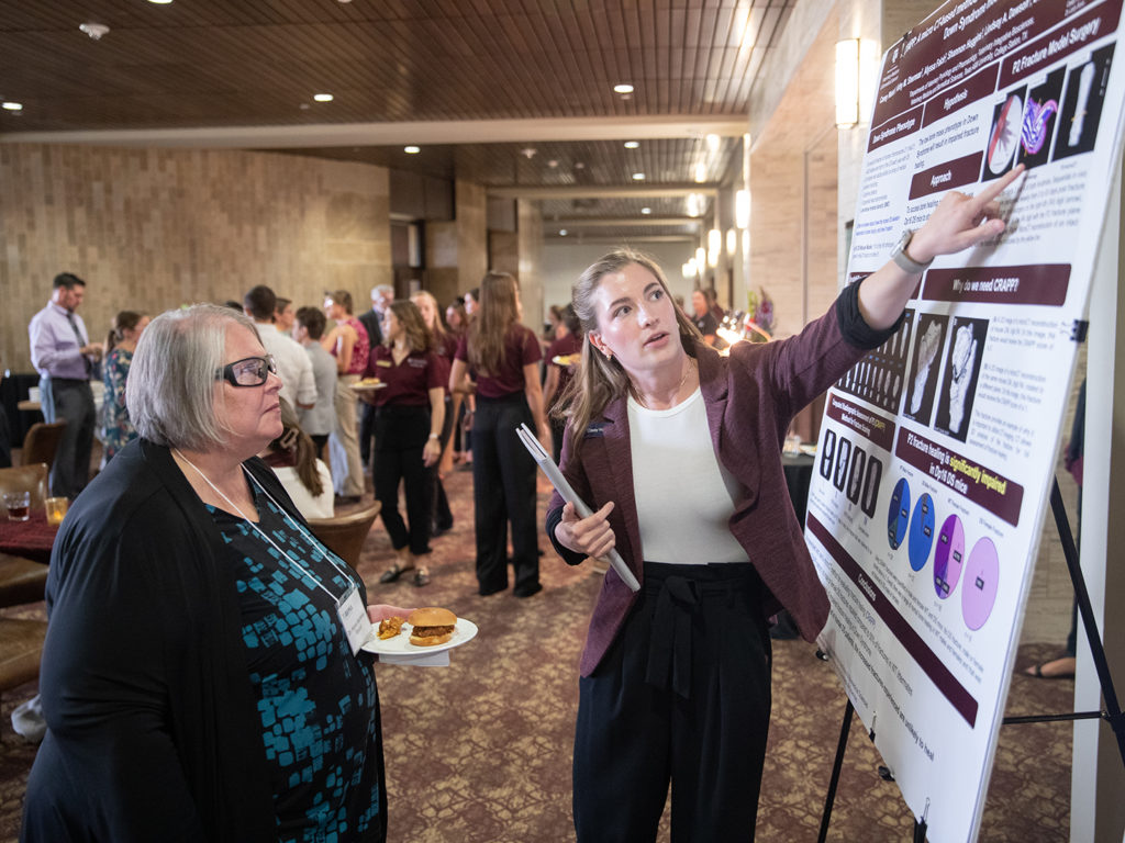 A veterinary student discusses her research poster with a member of the AVMA COE
