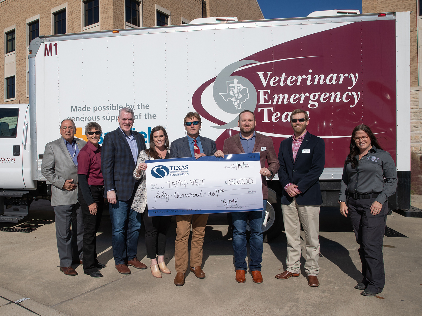 Members of the Texas A&M Veterinary Emergency Team and Texas Veterinary Medical Foundation holding a giant check for $50,000 in front of a VET trailer