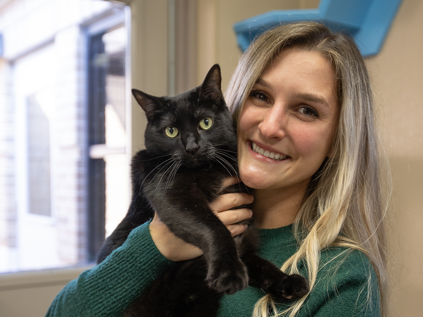 A veterinary student holding a black cat