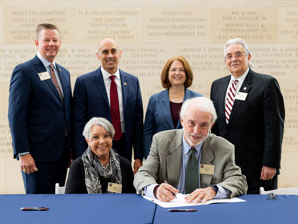 Linda and Dennis Clark signing their gift agreement, with university officials standing behind them