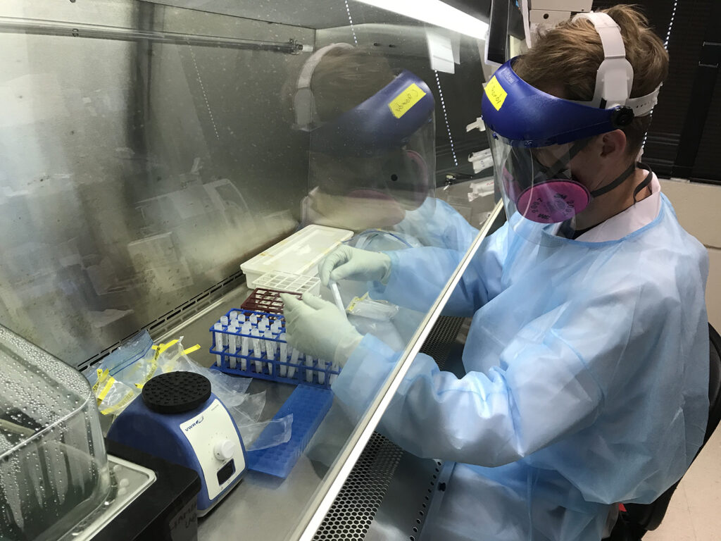 A researcher in full PPE working in a lab