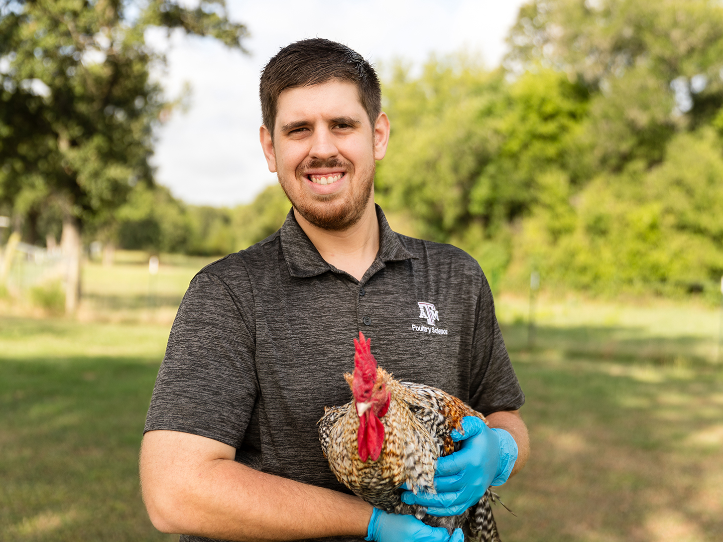 Nikolas Faust in a Texas A&M Poultry Science shirt holding a rooster