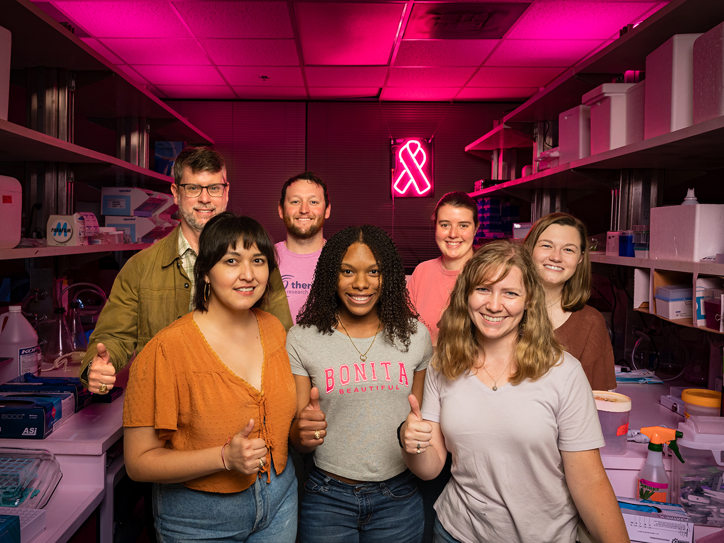 A group of people in the Porter lab, which is lit up with pink lights