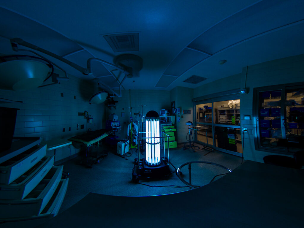 Trudy the UV robot in use, emitting blue light in an operating room