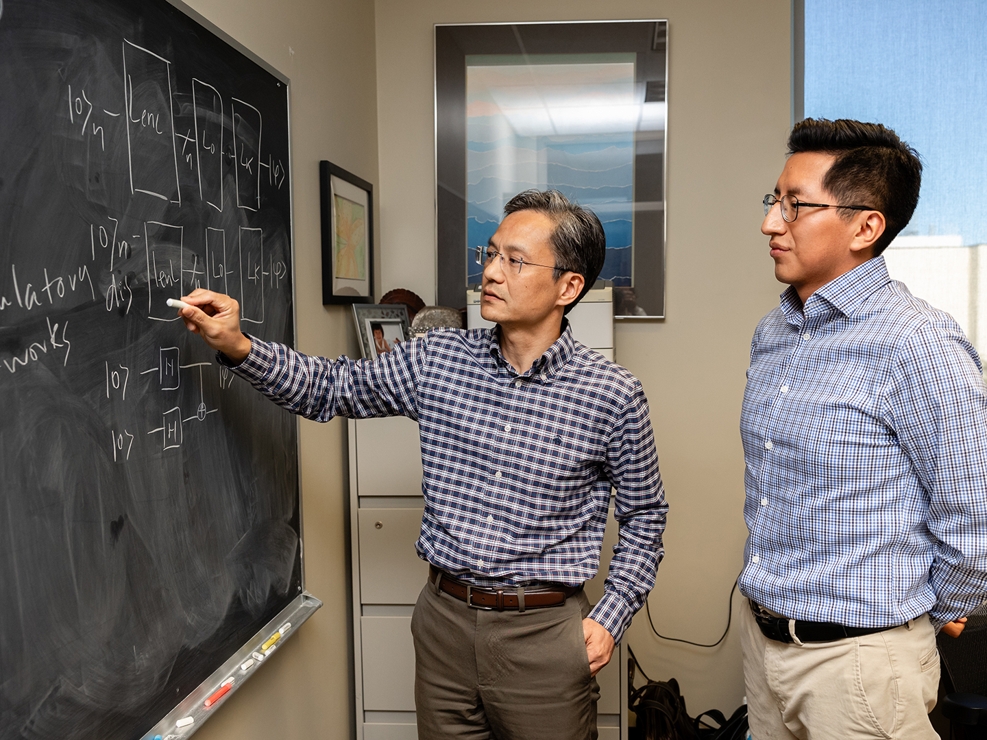 Dr. James Cai and Cristhian Roman Vicharra working on a chalkboard