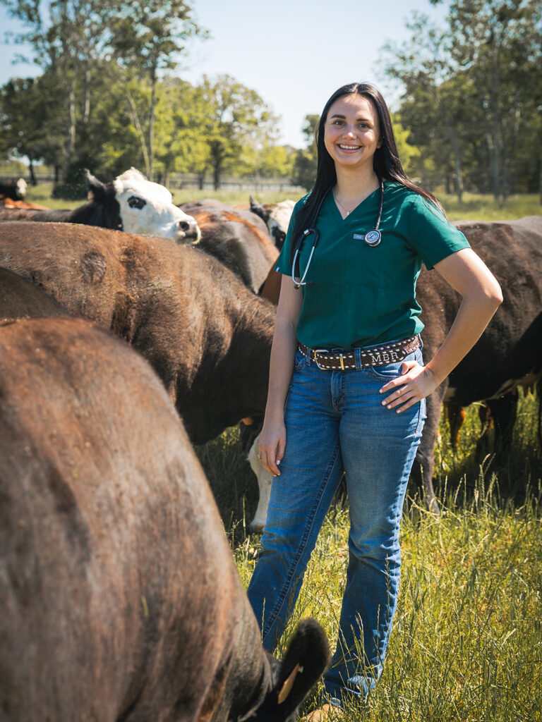 Madison Roberds standing in a field among beef cattle