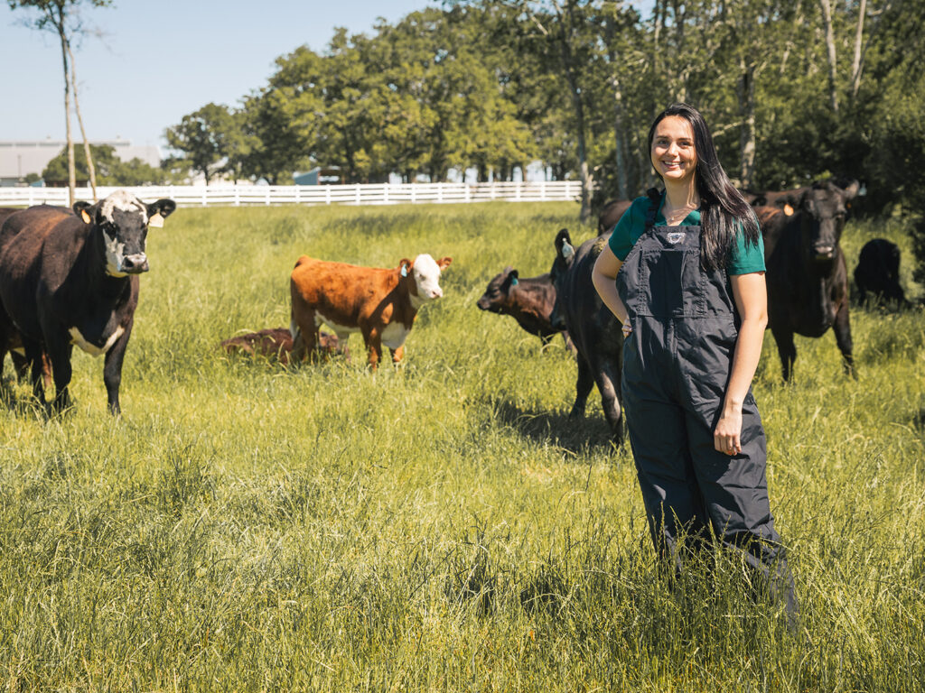 Roberds in coveralls in a field with beef cattle