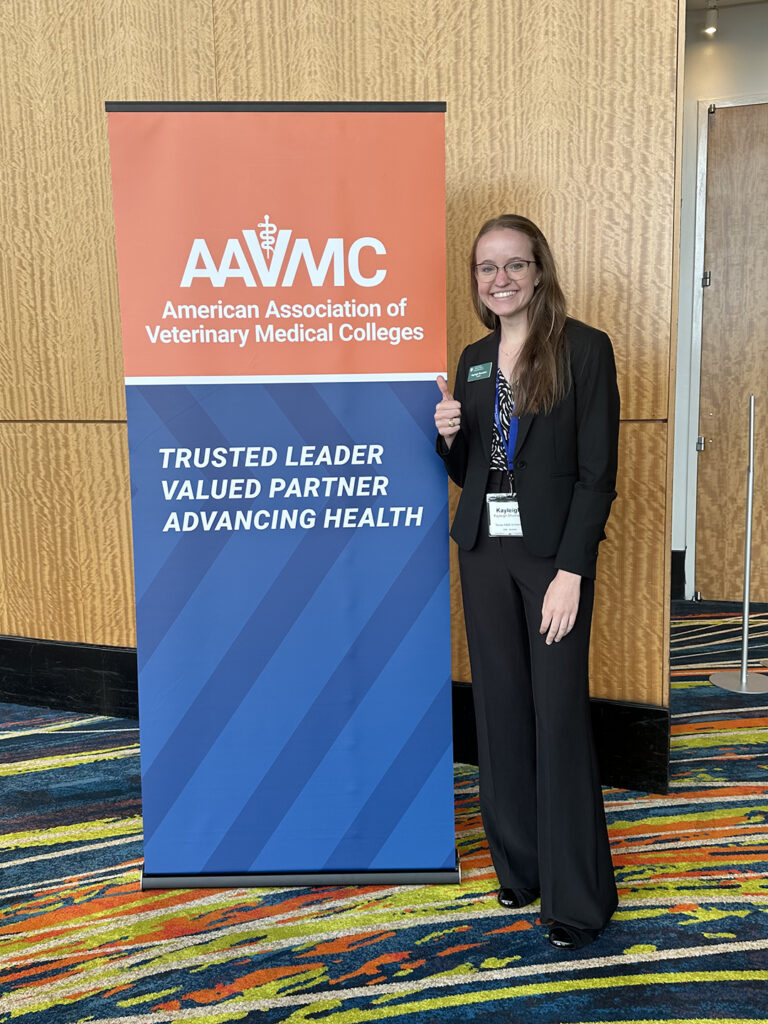 Kayleigh Shumaker gig 'ems next to the AAVMC conference sign