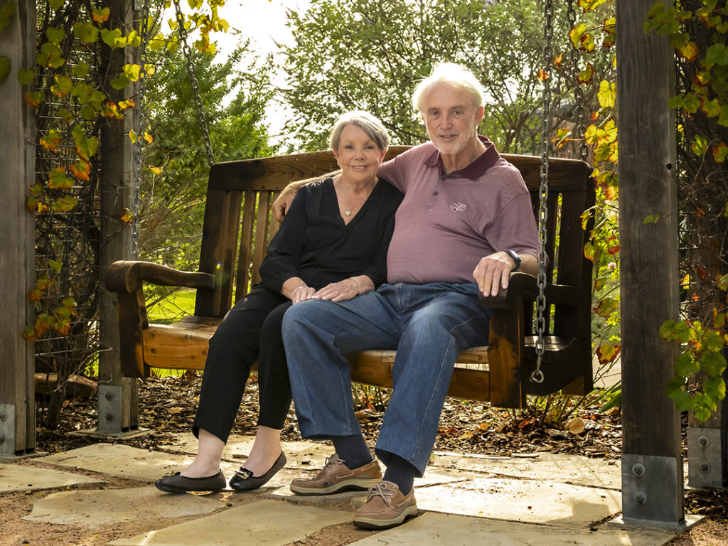 Linda & Dennis Clark ’68 ’71 sitting on a bench swing outside